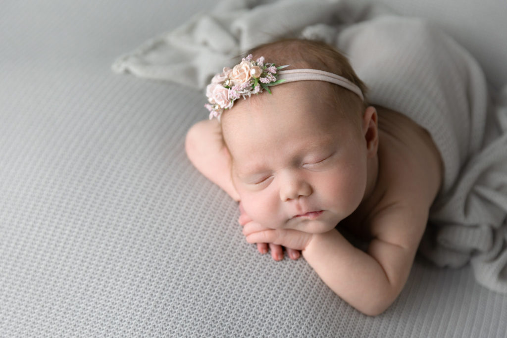 Newborn baby girl sleeps on a grey blanket, by Crystal Lee Photography.